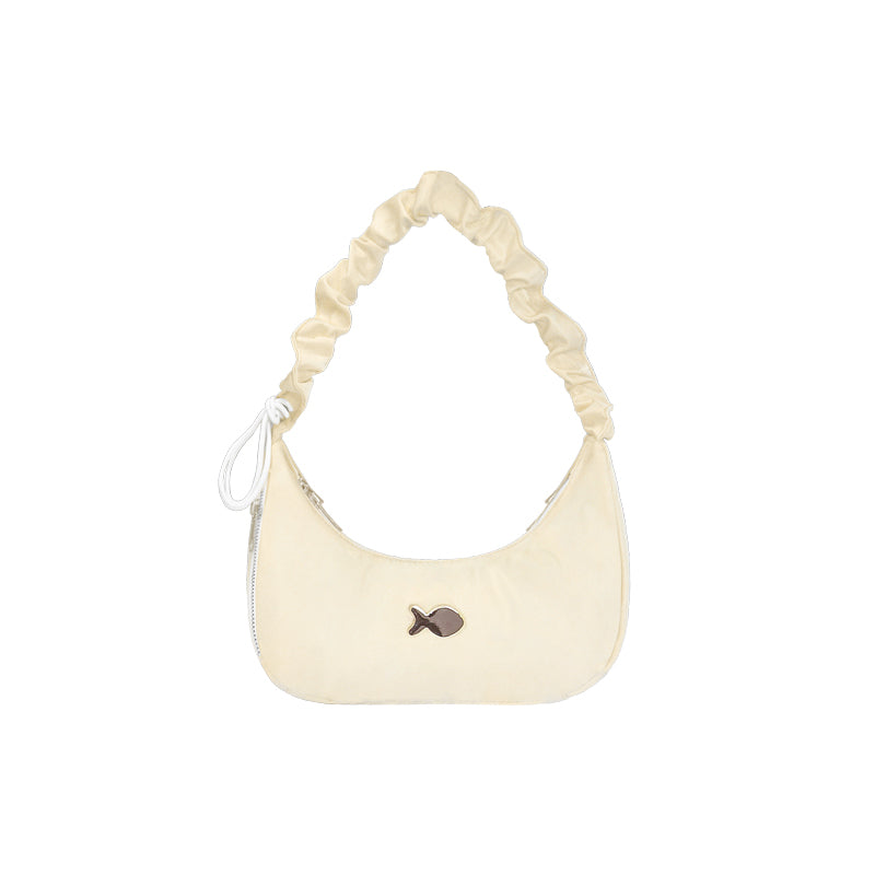 Cream-colored handbag with a fish charm on a white background