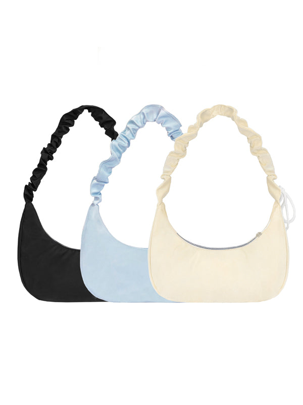 Three shoulder bags in black, blue, and beige on a white background