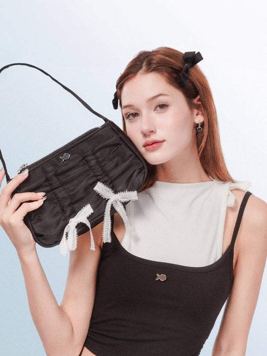Woman holding a black clutch bag with tassels against a light blue background