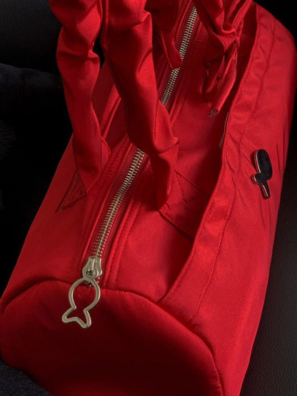 Close-up of a red jacket with a zipper and a small charm on a dark background