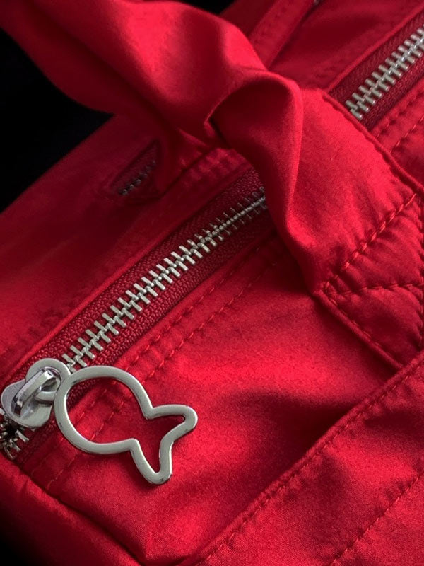 Red jacket with a silver zipper and fish-shaped zipper pull on a black background