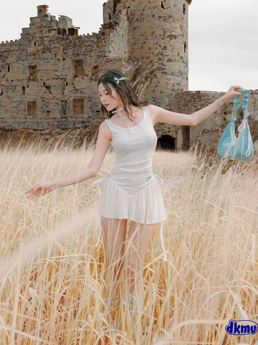 Woman in a white dress standing in a field with a castle in the background