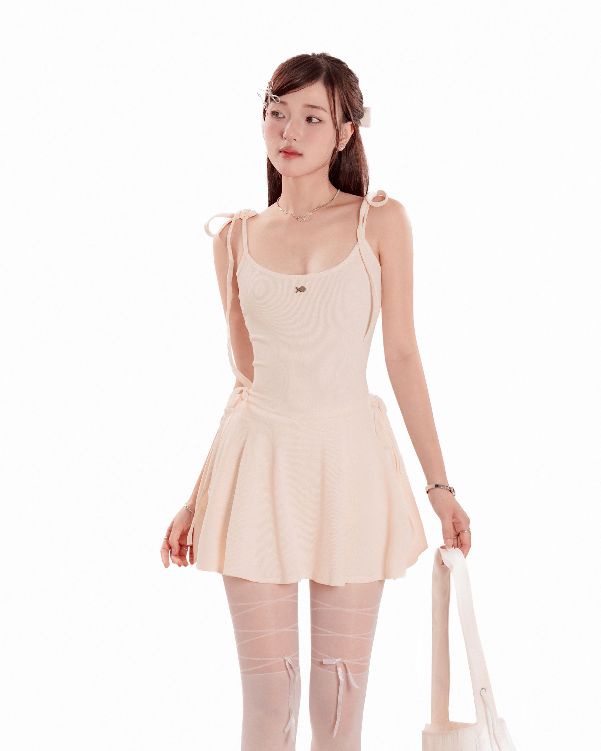 Woman wearing a beige dress with sheer stockings on a white background