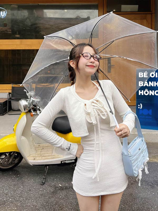 Woman holding a transparent umbrella in an urban setting with a scooter and store in the background.