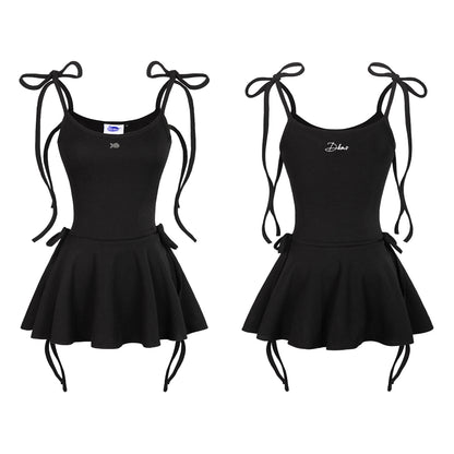 Two black dance leotards with skater skirts and tie straps on a white background.