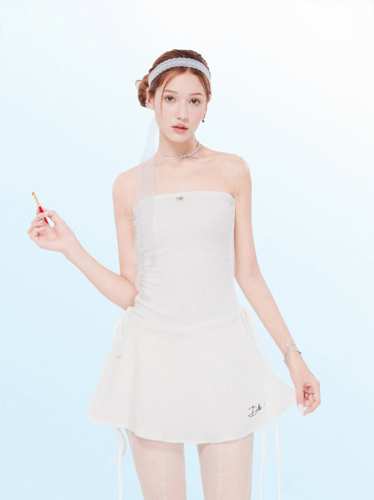Woman wearing a white strapless dress against a light blue background