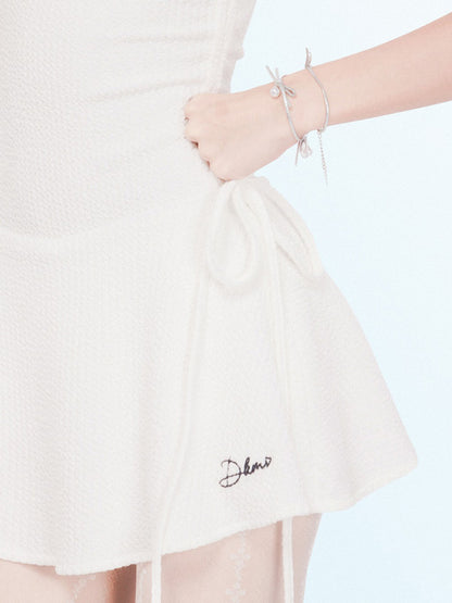 White skirt with 'Delave' embroidery held by a hand on a light pink background