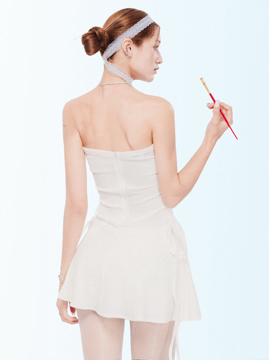 Woman in a white dress holding a red brush against a light blue background