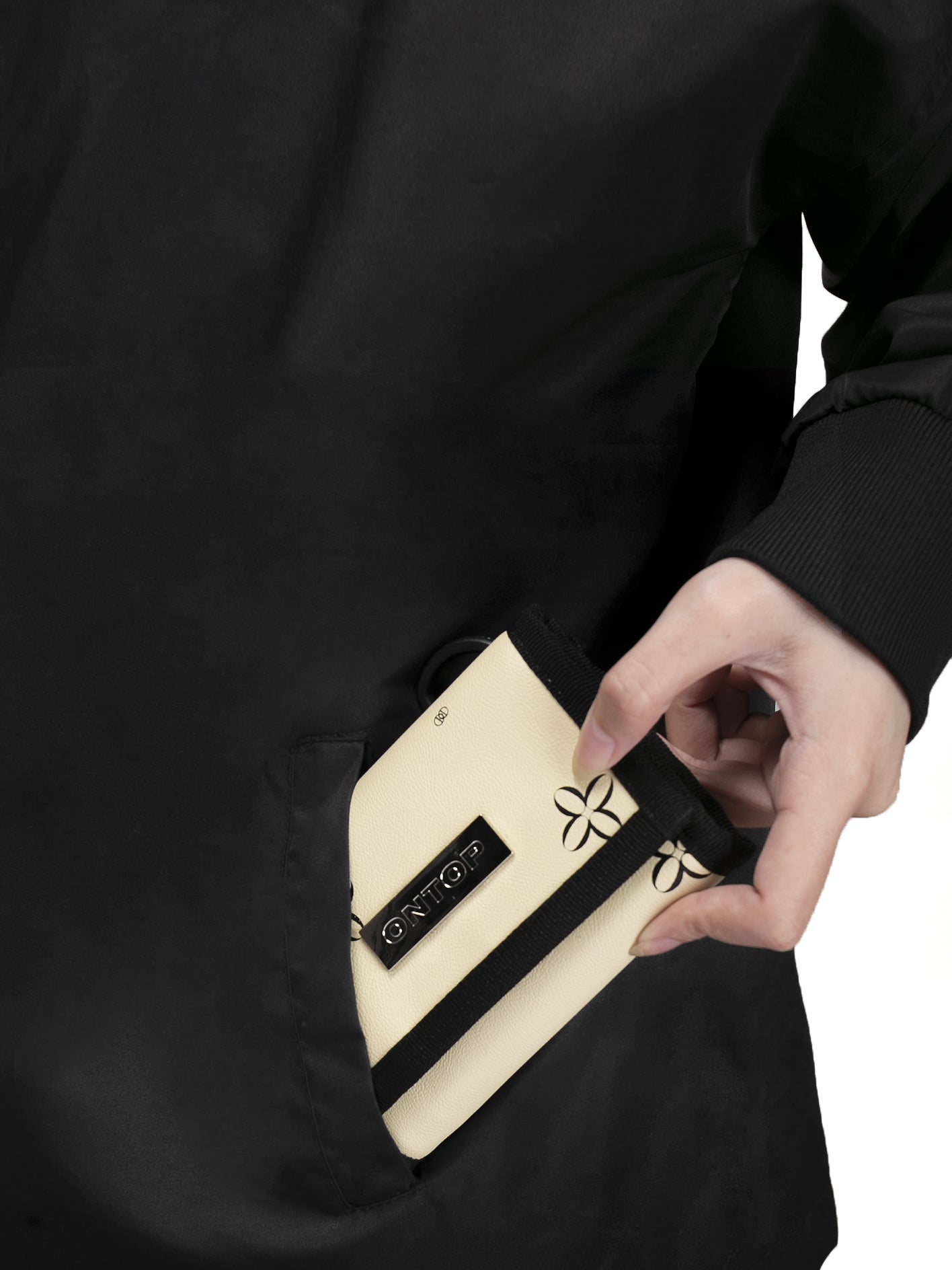 Person holding a black and beige pouch with a brand logo on a white background