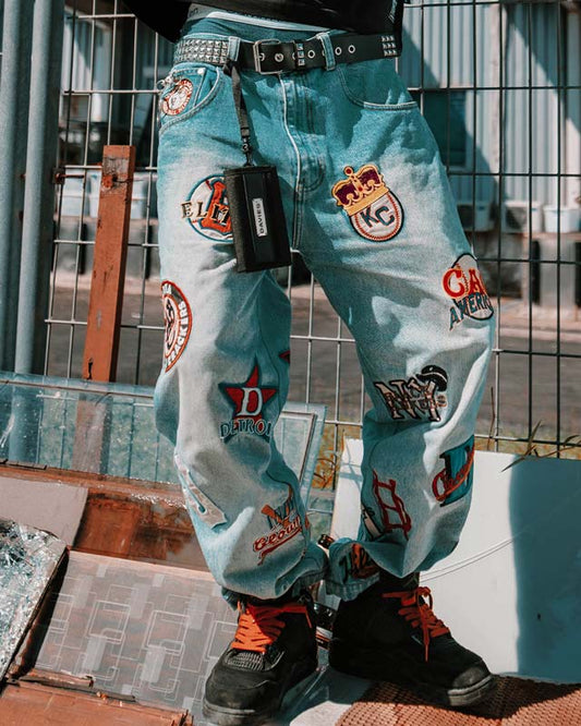 Light blue jeans with various patches worn by a person on an outdoor setting.