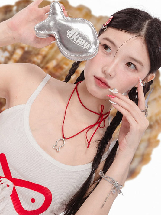Woman holding a silver product with 'dkmv' branding, wearing a white tank top with red designs.